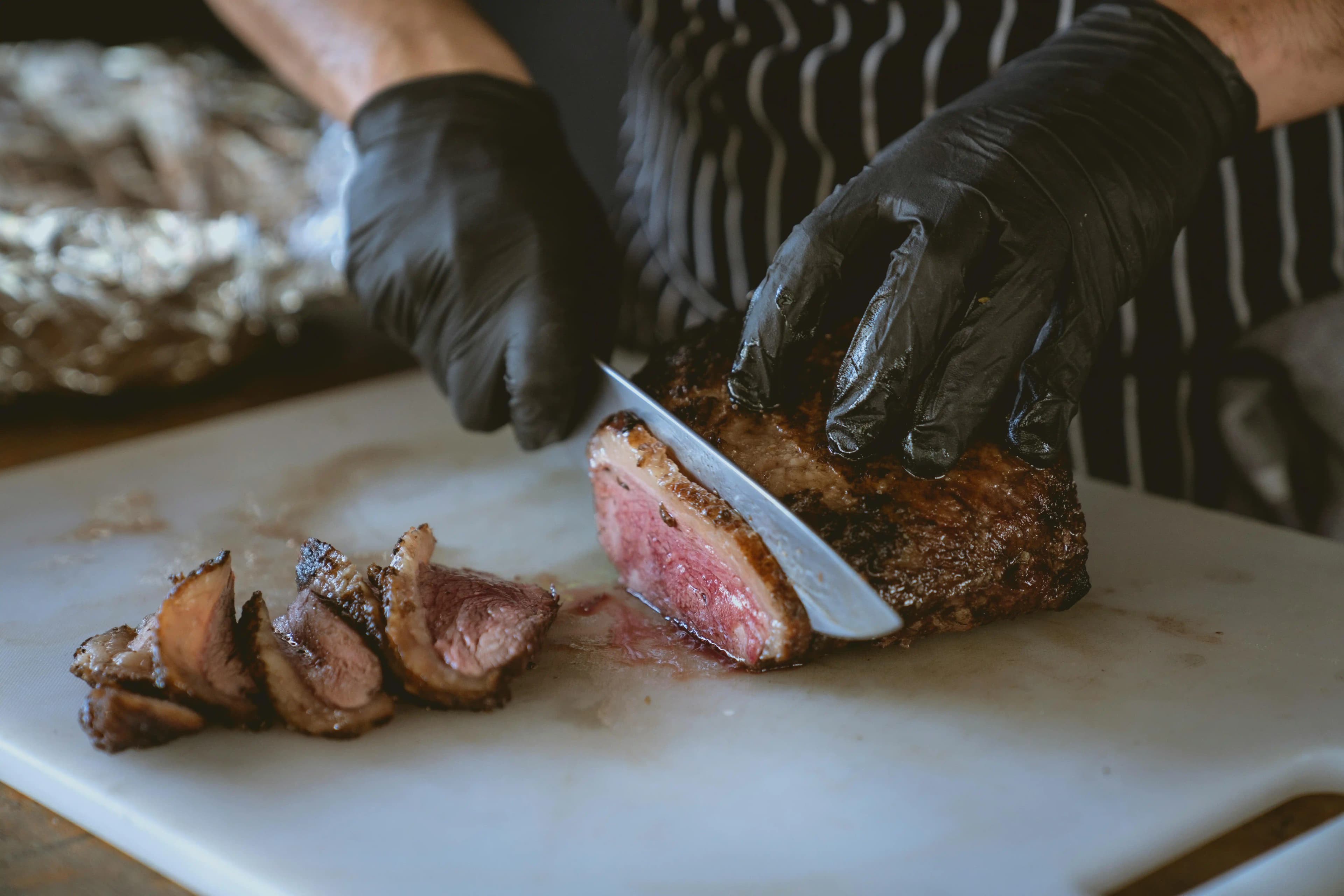 A chef slicing steak with a knife.