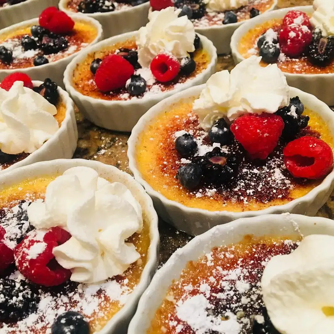 Berry creme brulee ramekins finished with whipped cream and powdered sugar.