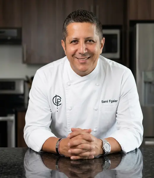 Chef Sami Fgaier seated at a kitchen counter.