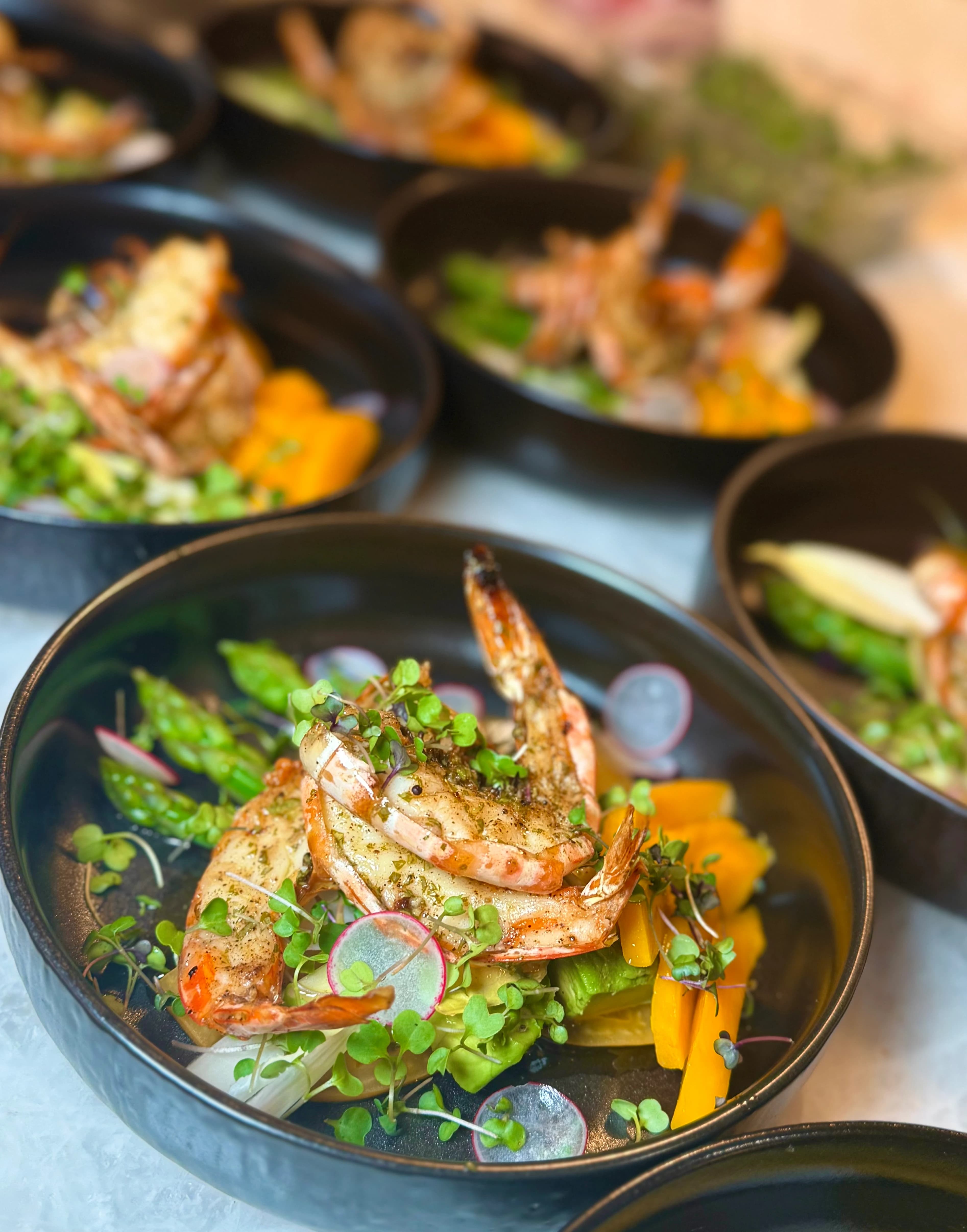 Grilled prawns and roasted asparagus plated with radish and microgreens.
