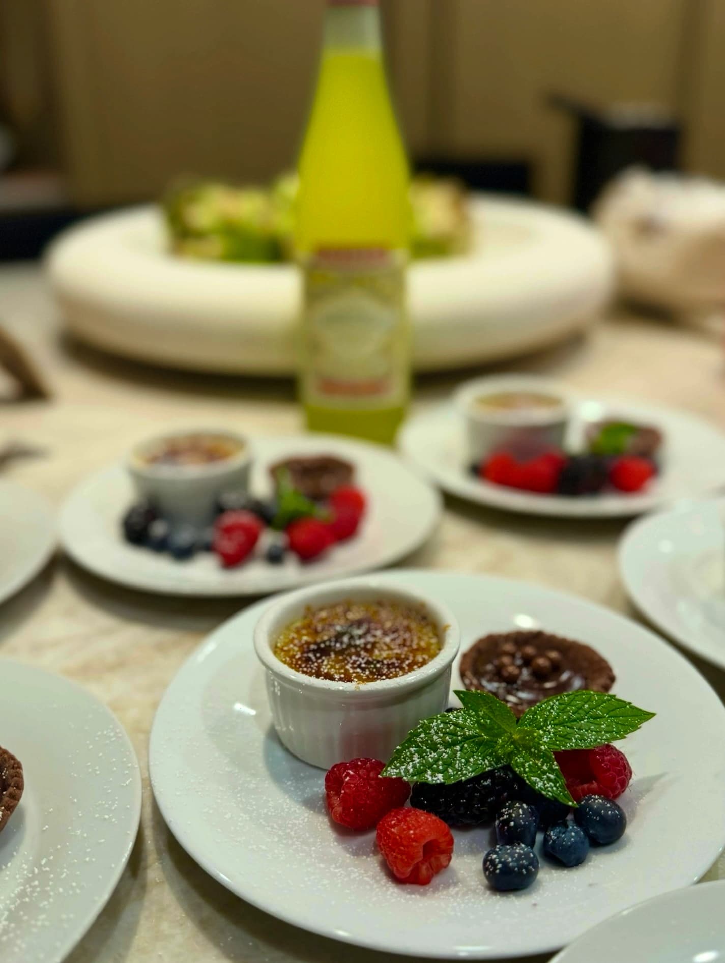 Mini creme brulees and chocolate tartlets plated with fresh berries and mint.